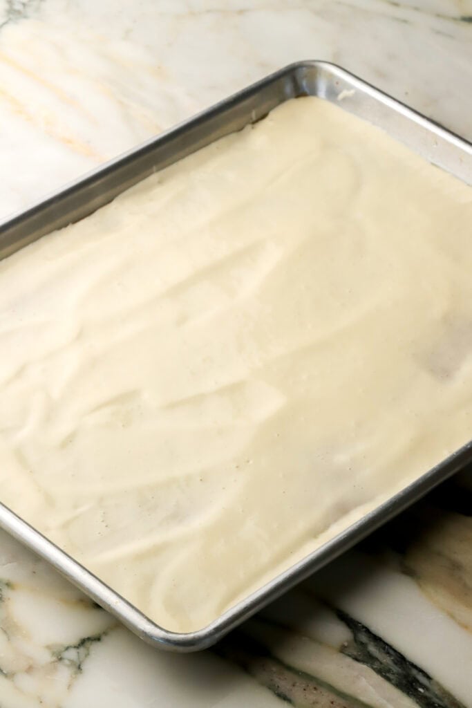 cake batter spread out as thin as possible on a lined sheet pan