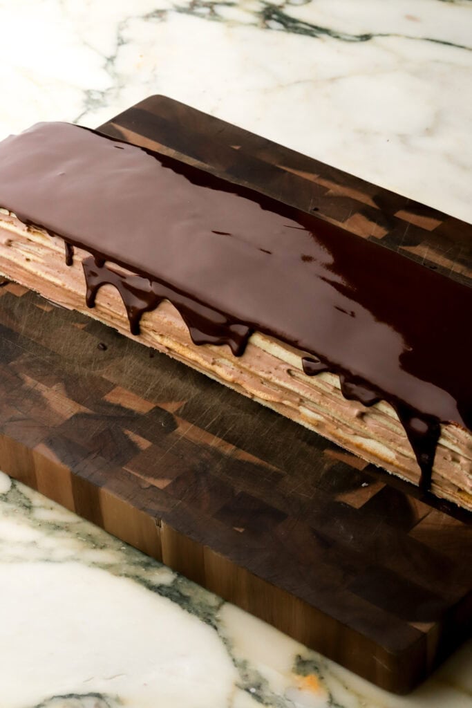 chocolate glaze spread on top of chilled cake, dripping off the edge