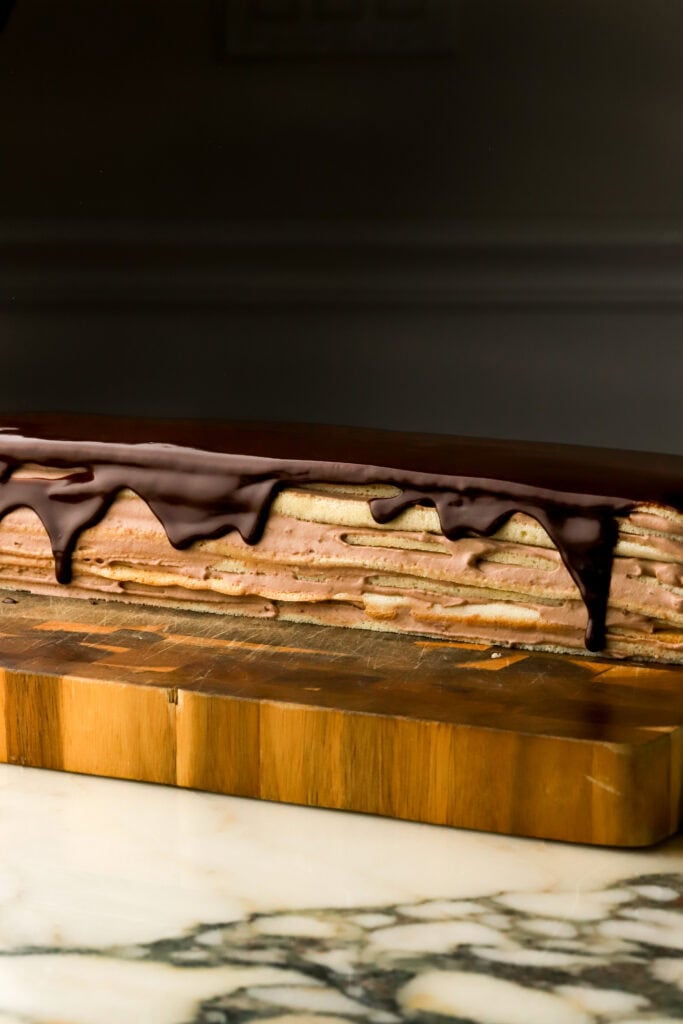 cake completely finished before slicing, on a wooden board on a marble countertop 