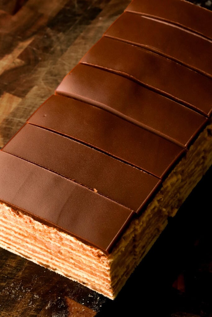 cake freshly sliced, showing top layer of chocolate with slices through it on a wooden board