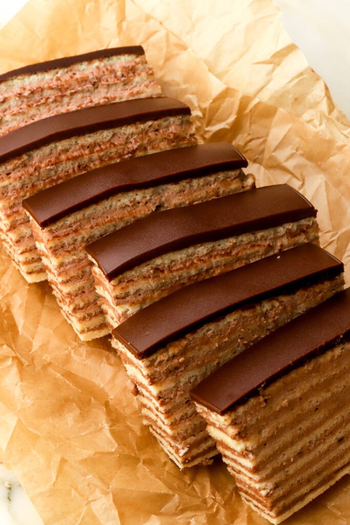 6 slices of dobos on a tray with brown parchment paper - sliced showing all the layers of cake