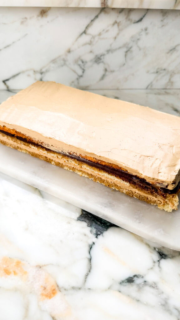 final layer of jaconde sponge on cake topped with coffee buttercream
