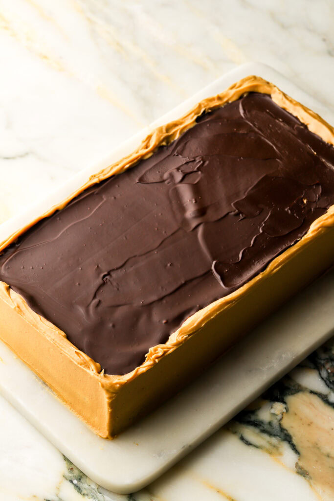 chocolate glaze on top of opera cake within a rough edge border of buttercream