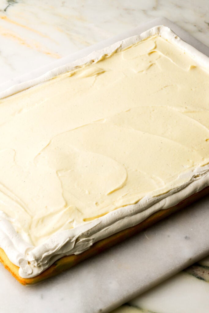 bottom layer of cake with frosting piped around the edge of the cake and custard filling in the center