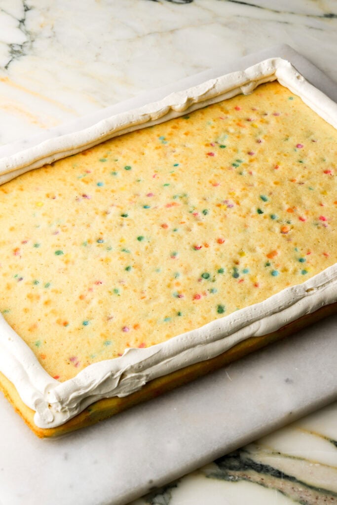 cake on a flat surface with frosting piped around the edge