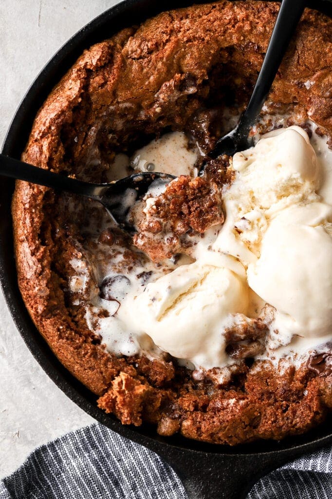 triple chocolate skillet cookie with ice cream and spoons
