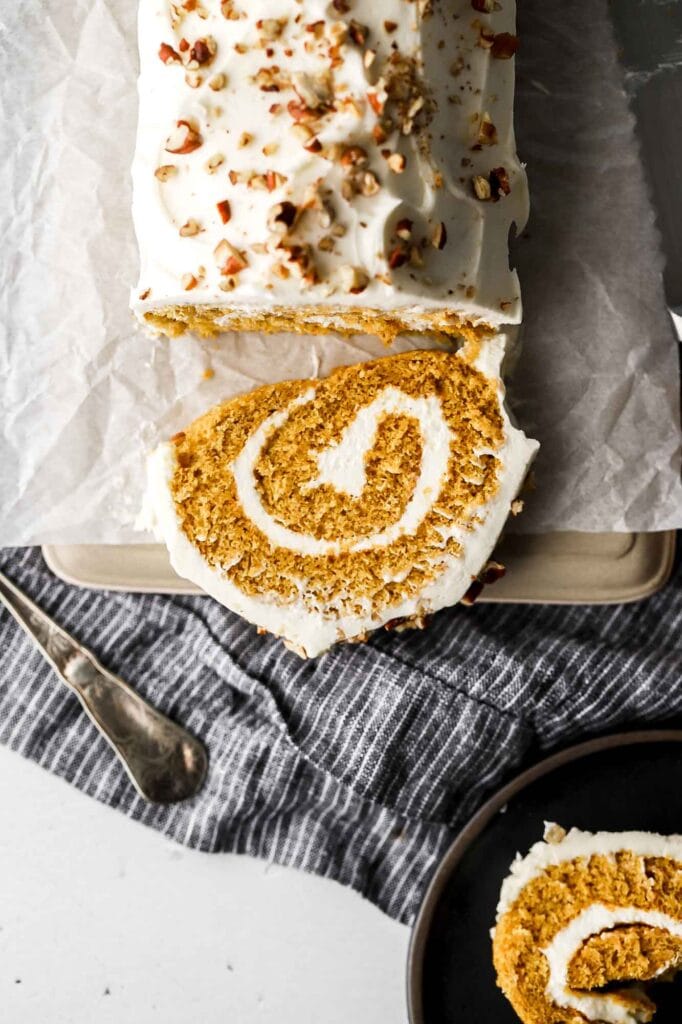 slice of pumpkin roll with cream cheese frosting and pecans