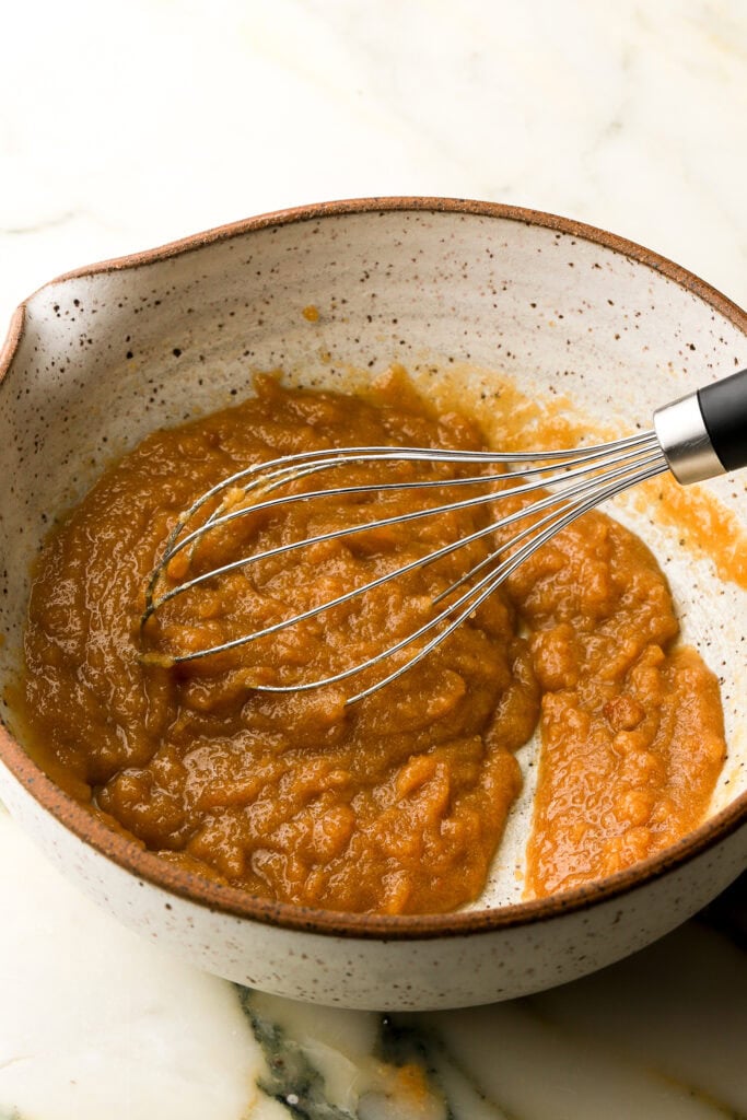 butter and sugar mixed together in a pottery bowl with a whisk 