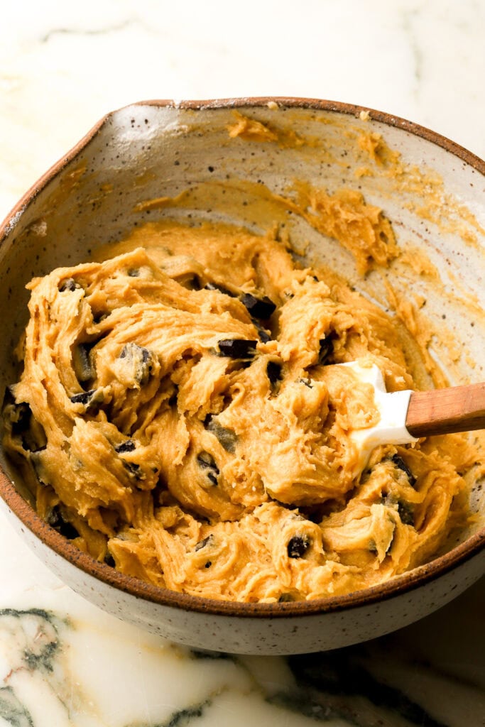 finished cookie dough mixed in a pottery bowl with a rubber spatula