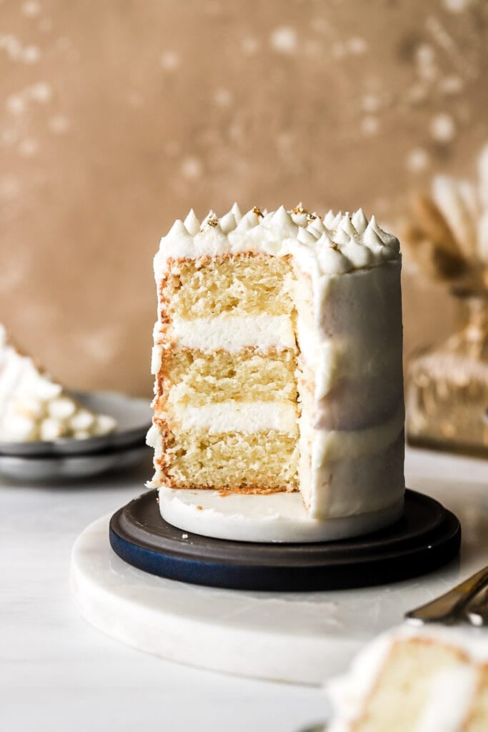 slice cut out of the cake to show three layers of vanilla cake and buttercream