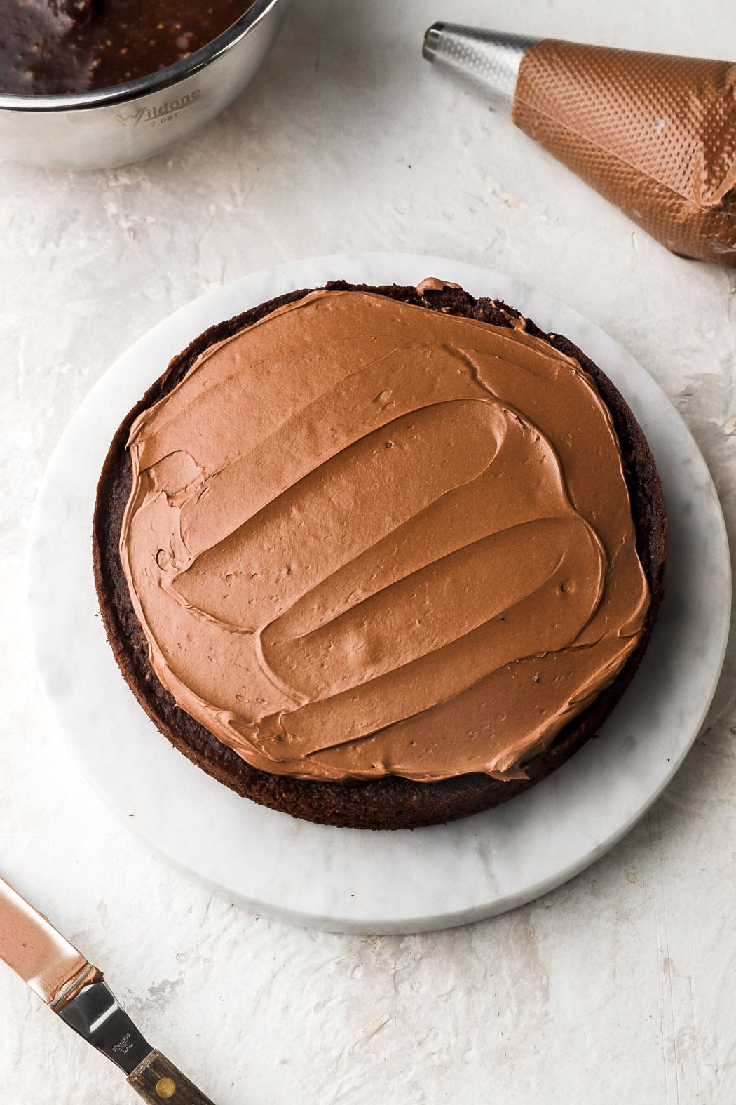 spread a thin layer of frosting on top of the cake