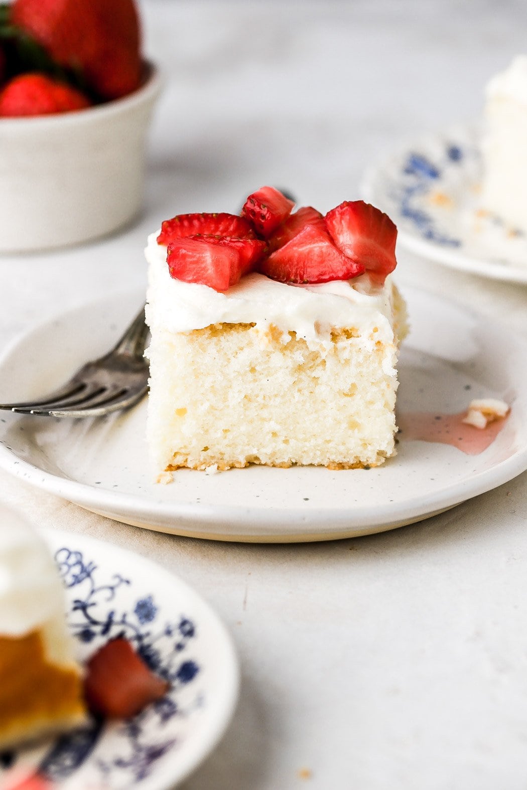 white cake with cream cheese frosting and strawberry topping