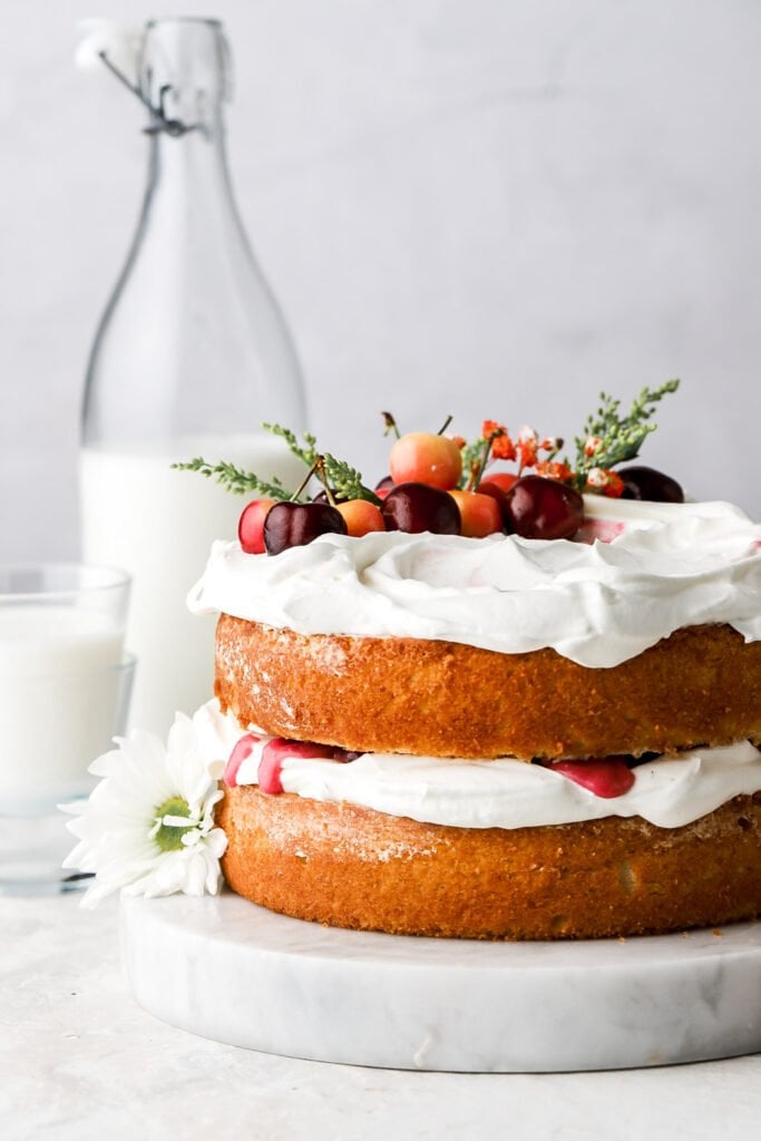 white forest cake with fresh cherries and flowers on top