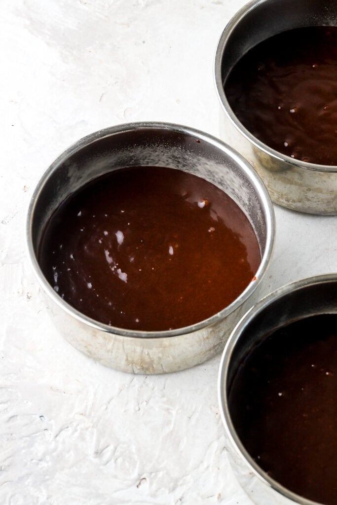chocolate cake batter in prepared cake pans