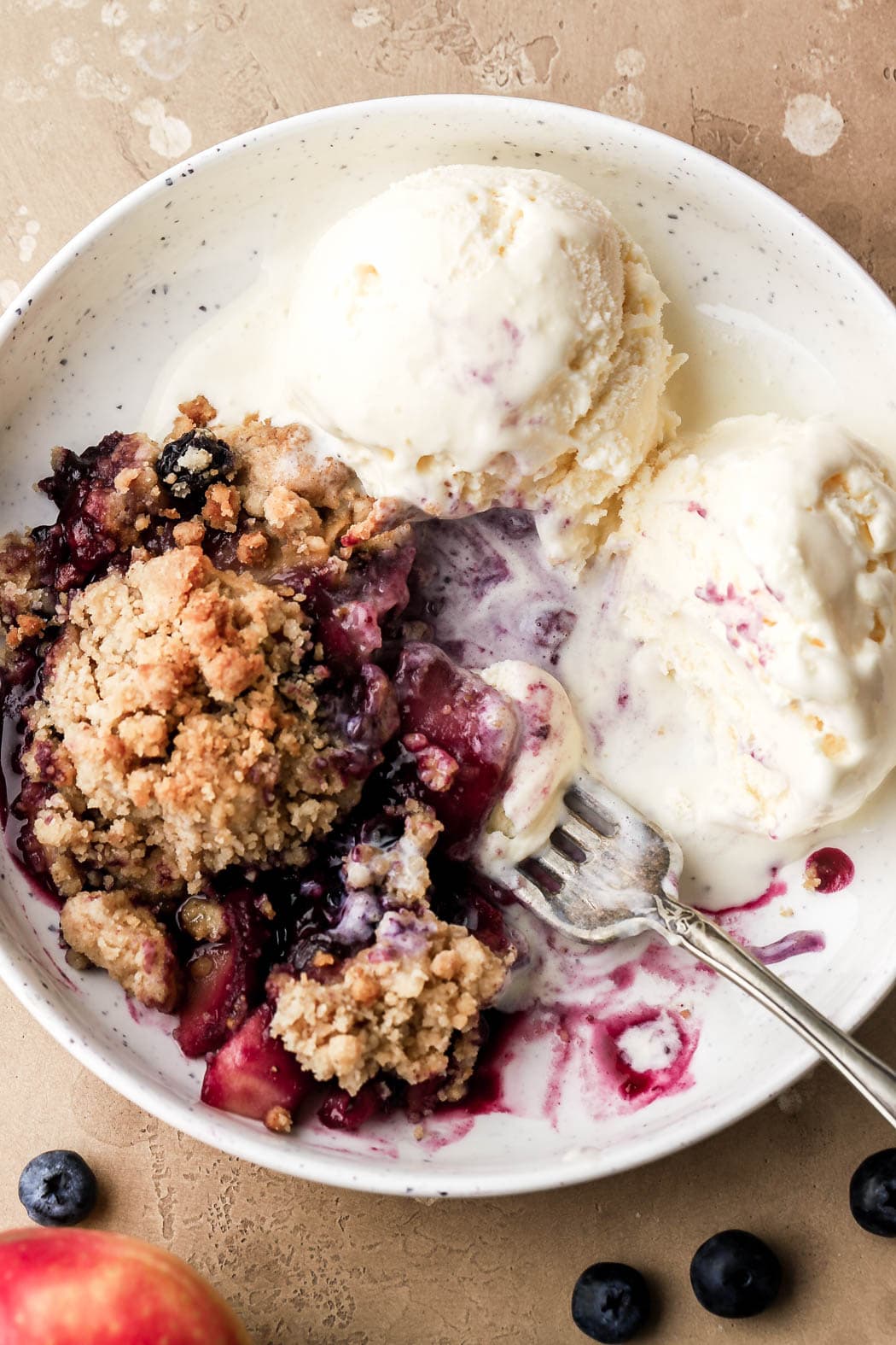 blueberries and apples with streusel topping and vanilla ice cream