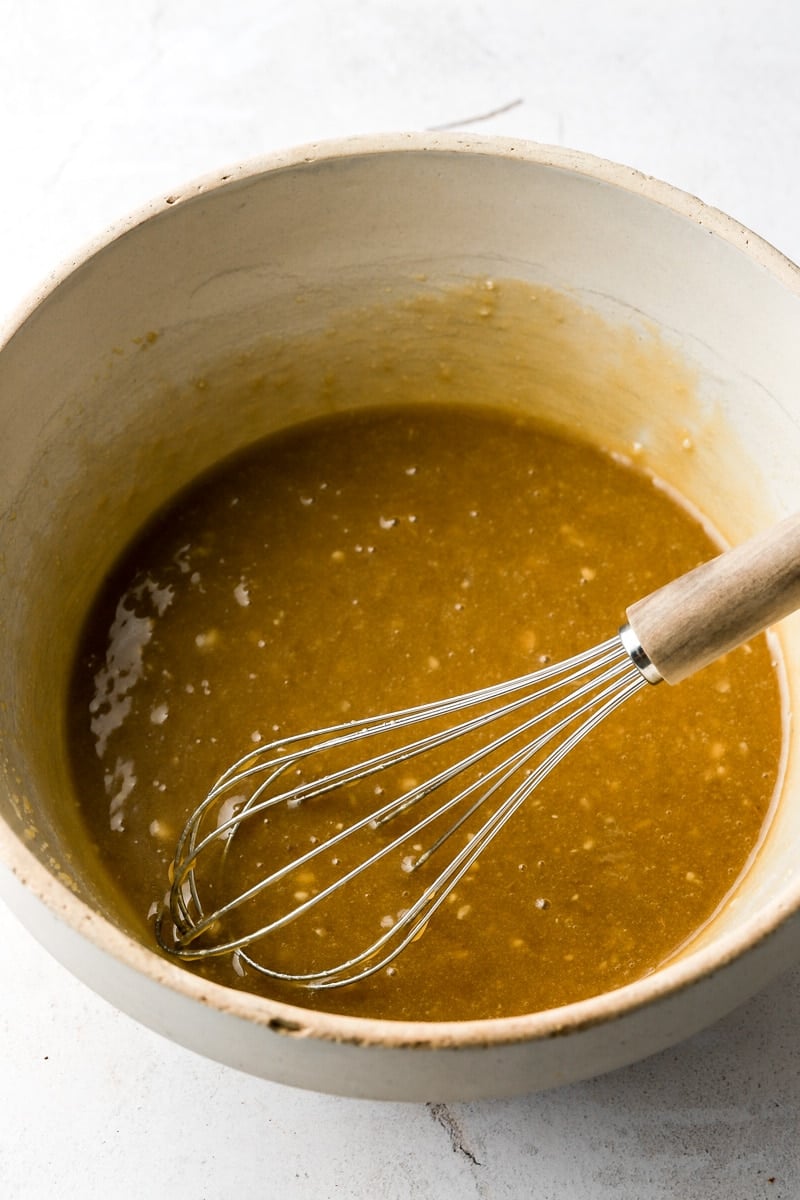 mashed bananas mixed with sugar and oil in a bowl with a whisk