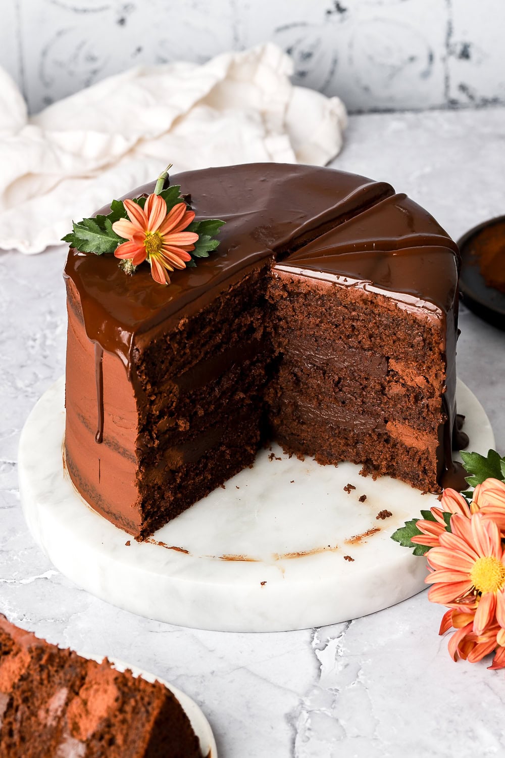 dark chocolate cake layered frosted with chocolate ganache and chocolate drip, slice missing showing the inside