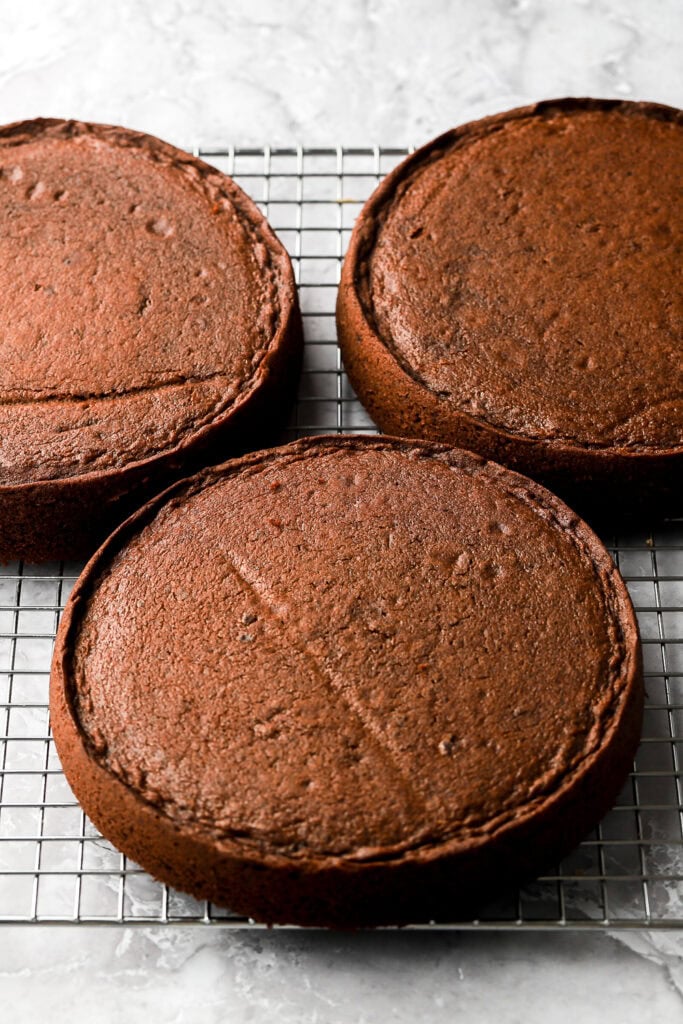three layers of chocolate cake on a cooling rack