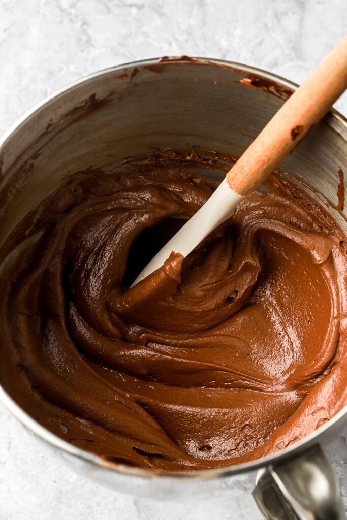 whipped chocolate ganache in a mixer bowl with a spatula