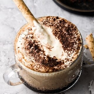 tiramisu latte with dusting of cocoa powder and a cappuccino cookie