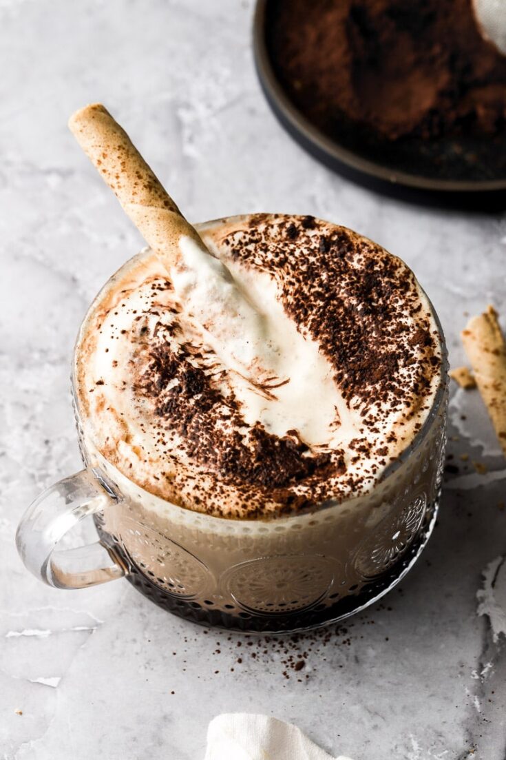 tiramisu latte with dusting of cocoa powder and a cappuccino cookie
