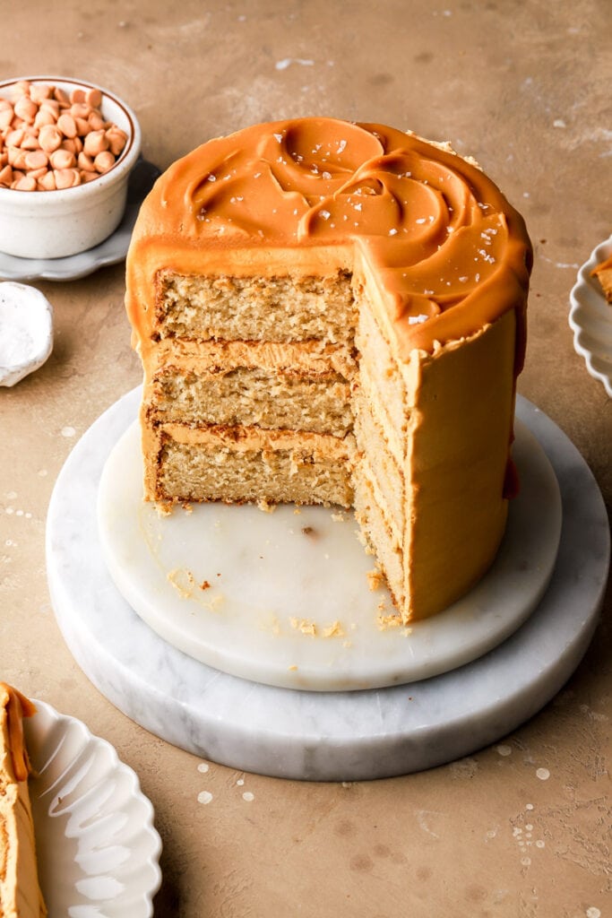 three layer butterscotch cake on a marble board sliced to show inside