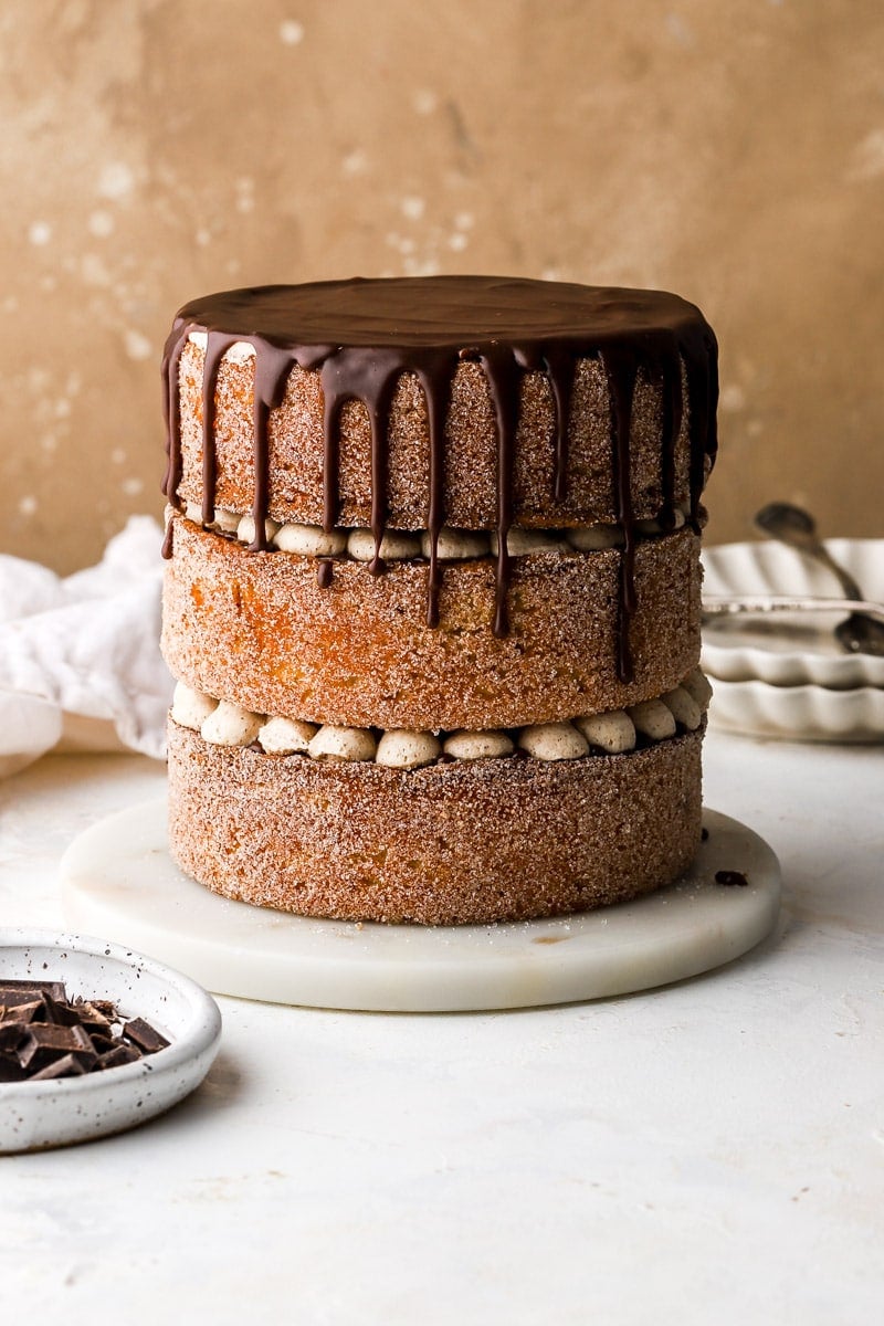 three layer churro cake covered in cinnamon sugar and chocolate sauce