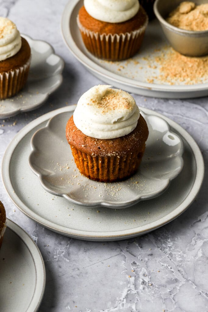 pumpkin cheesecake cupcakes on plates with graham cracker crumbs