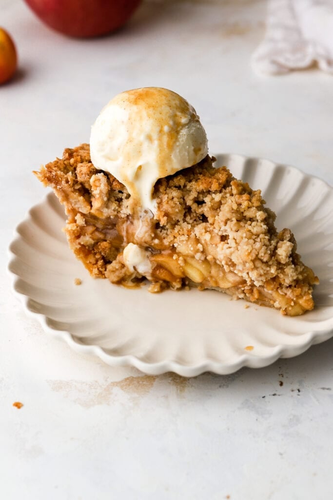 slice of dutch apple pie on a plate with ice cream on top.