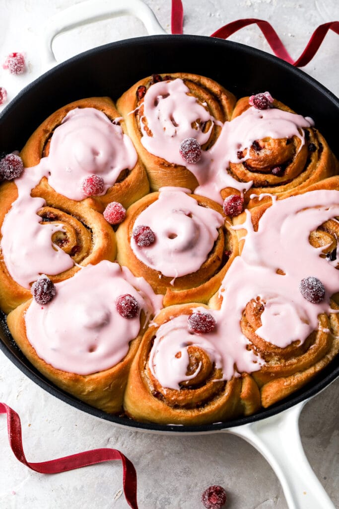 9 cranberry orange cinnamon rolls with cranberry glaze and sugared cranberries.
