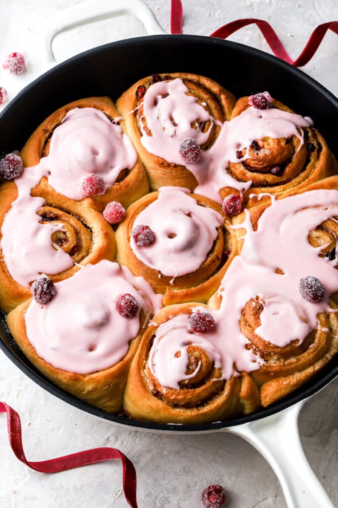 9 cranberry orange cinnamon rolls with cranberry glaze and sugared cranberries. 