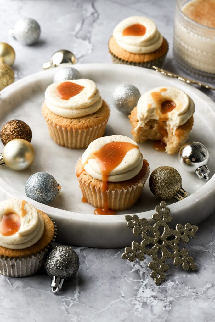 eggnog cupcakes with caramel drip on a plate with ornaments