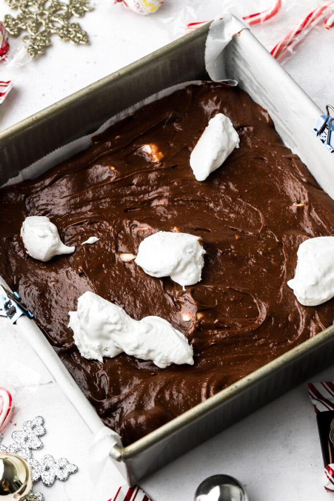 spread 2/3 of the brownie batter in the pan , top with globs of marshmallow fluff