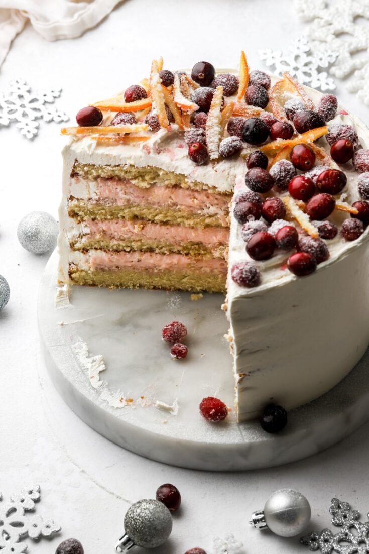 orange and cranberry cake sliced open with cranberries and orange peels on top