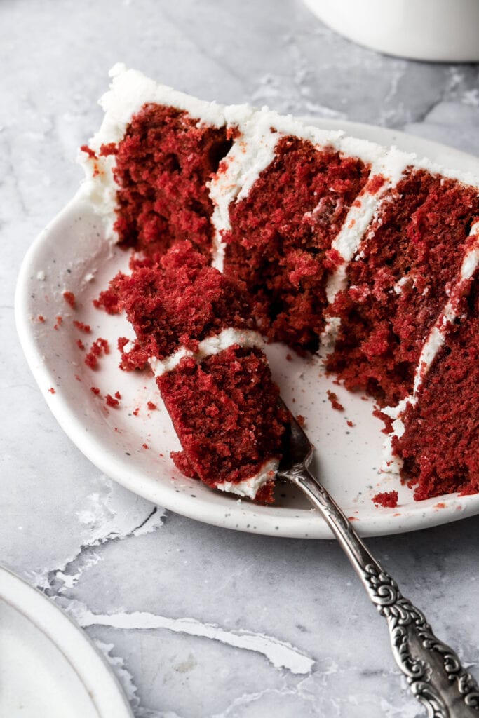 up close shot of red velvet cake on a plate with a fork digging in