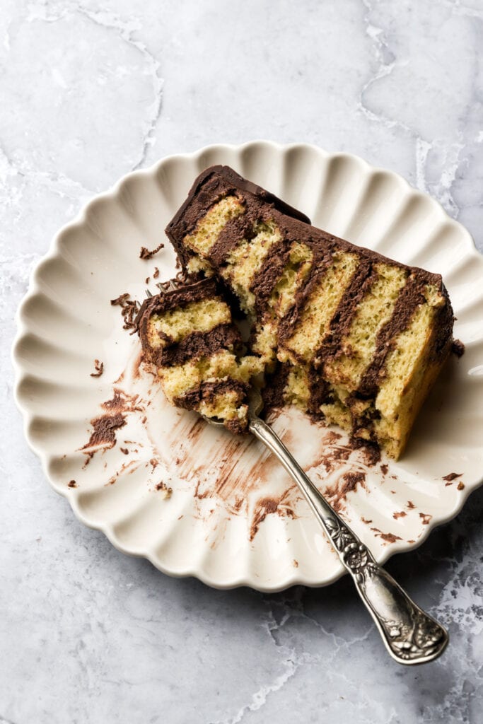 slice of cake on a plate with a few bites taken out and a fork