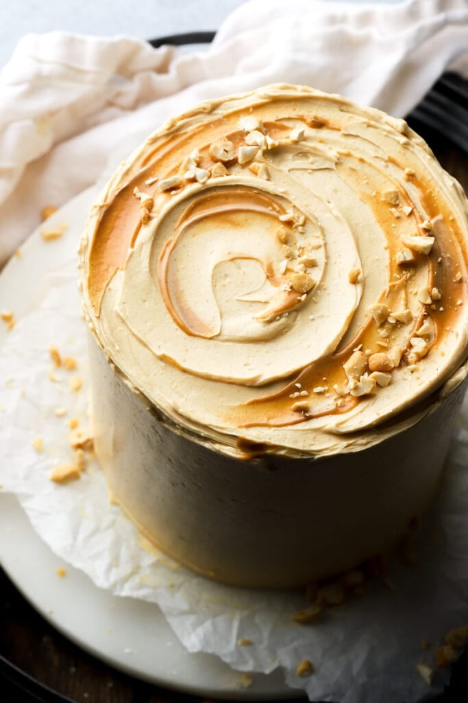 peanut butter frosting with peanut butter swirls and chopped peanuts on the top of a cake