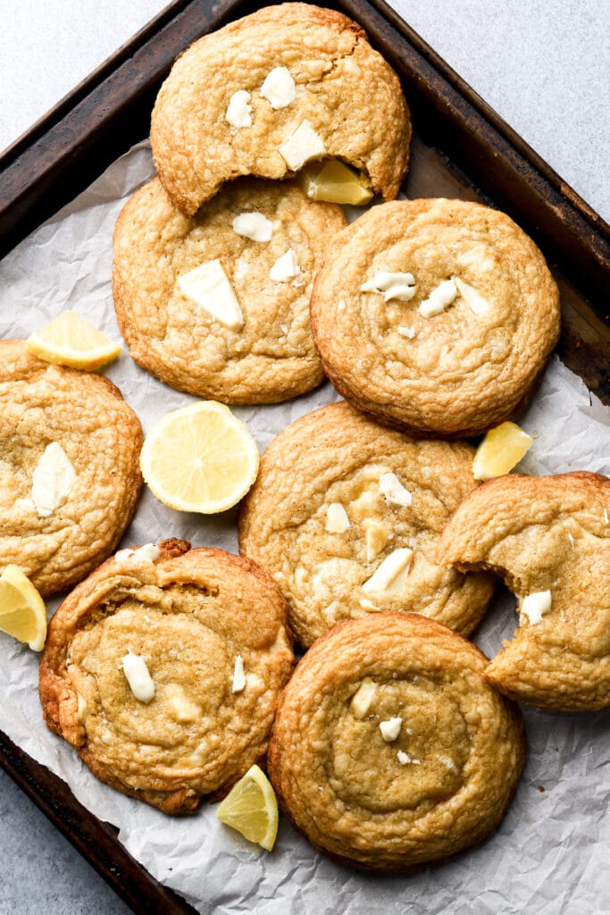 lemon white chocolate cookies on a cookie sheet with lemon slices