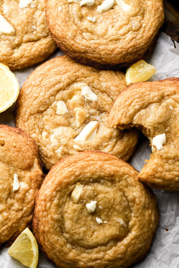 lemon white chocolate cookies on a parchment sheet with lemon slices