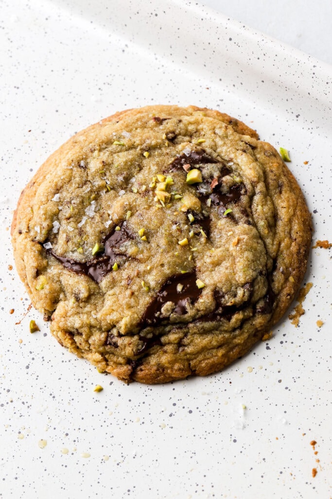 cookie cooling on a pan with melted pools of dark chocolate, sea salt and chunks of pistachio