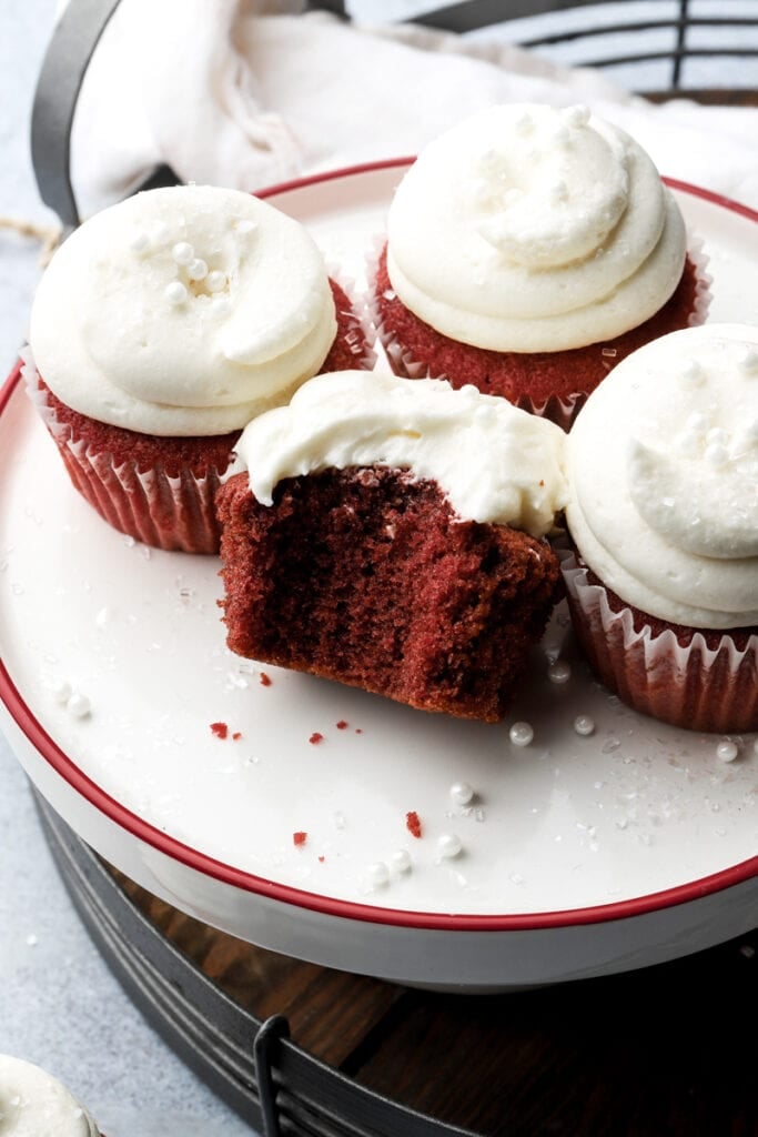 five red velvet cupcakes frosted with cream cheese frosting and bite taken out