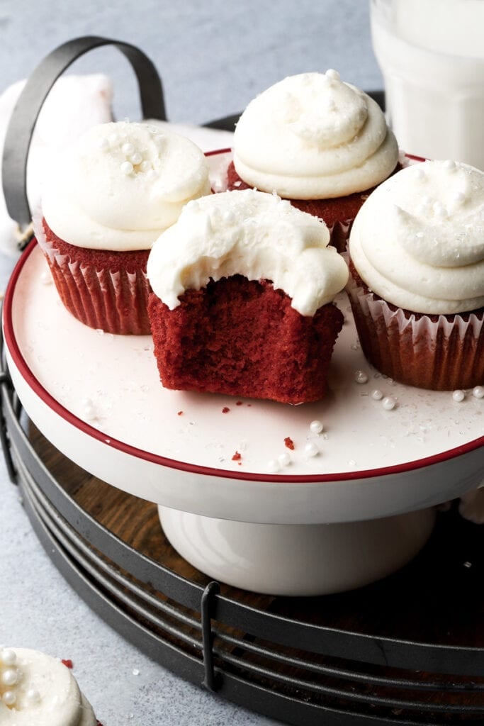 five red velvet cupcakes frosted with cream cheese frosting and bite taken out