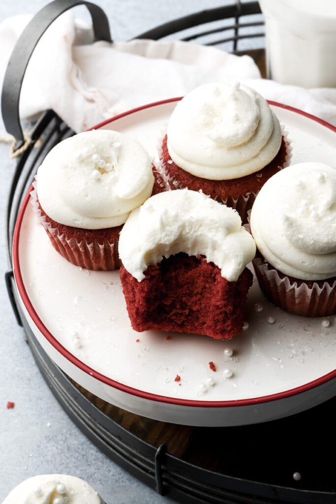 five red velvet cupcakes frosted with cream cheese frosting and bite taken out