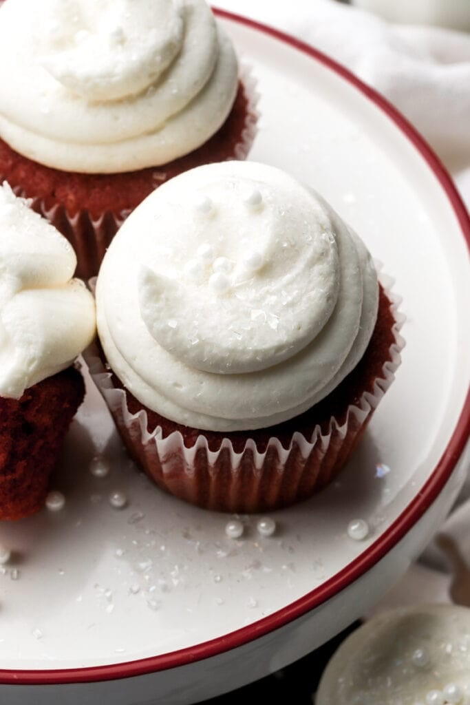 Four red velvet cupcakes frosted with cream cheese frosting