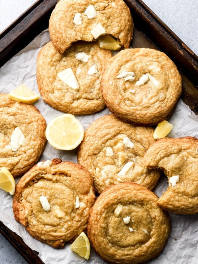 lemon white chocolate cookies on a cookie sheet with lemon slices