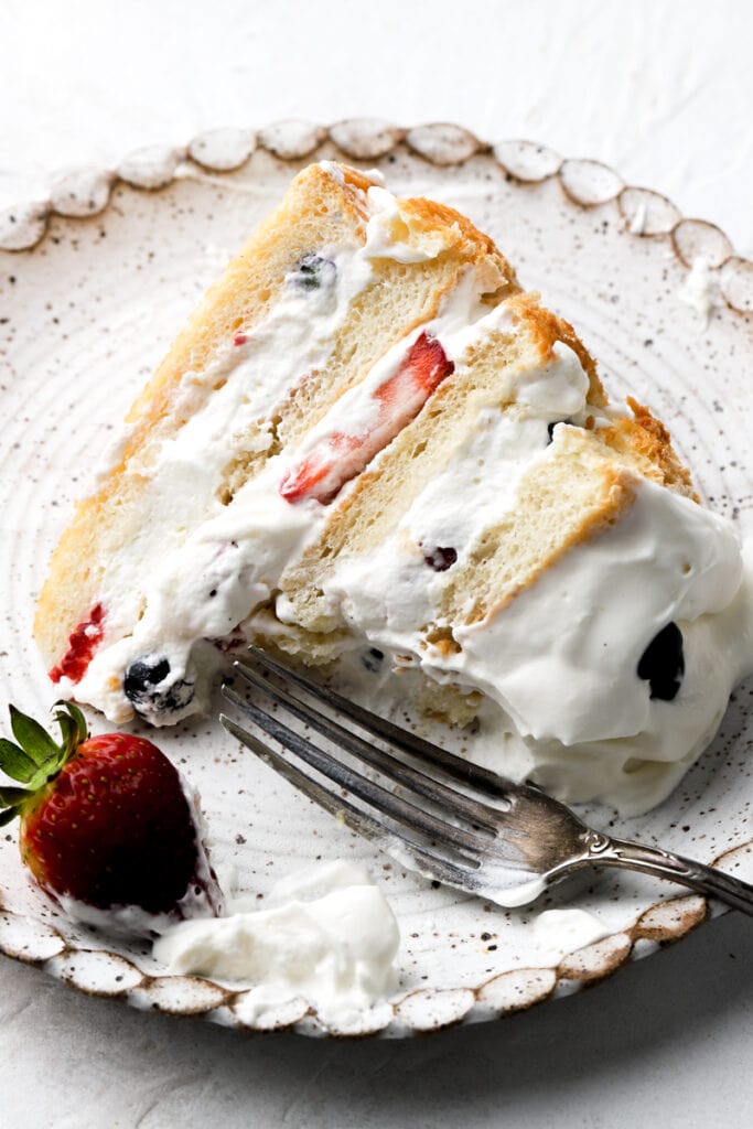 slice of chantilly cake on a plate with a bite taken out