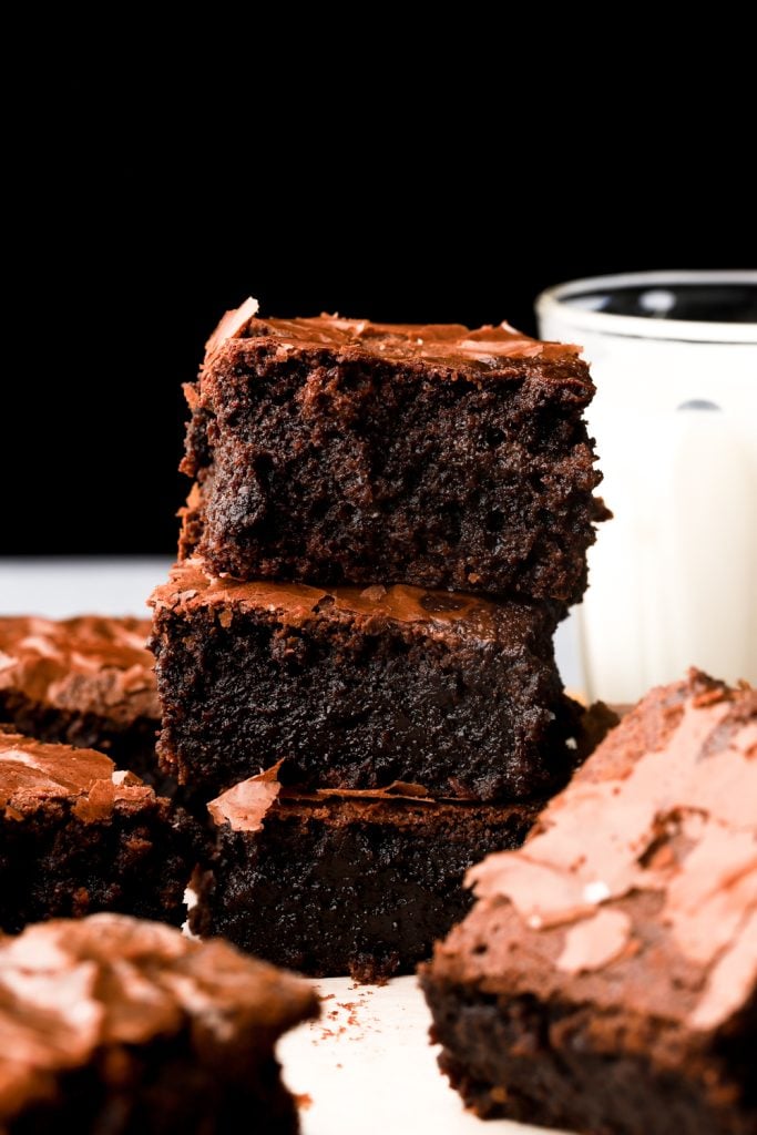 brownies stacked with with a glass of milk behind