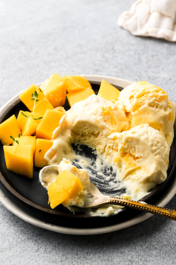 mango ice cream on a plate with fresh mangos