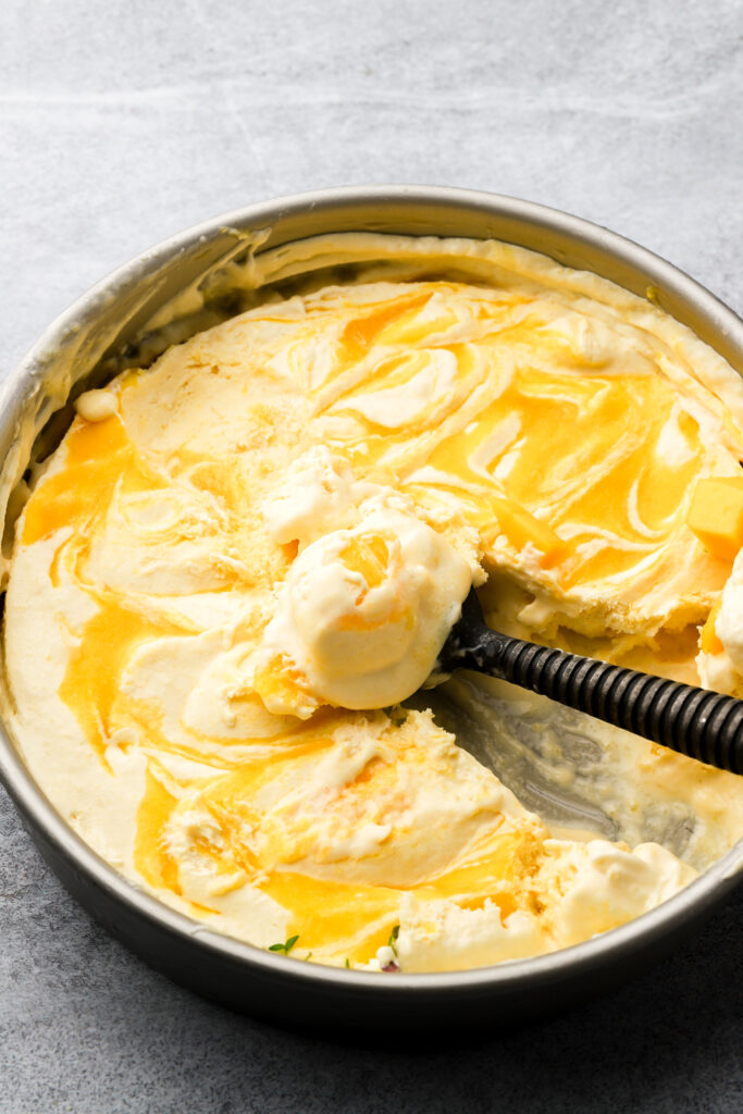 mango ice cream being scooped out of pan