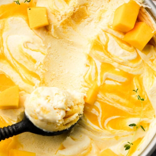 Mango ice cream with mango puree swirls and an ice cream scooper